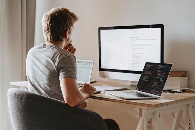 Person working across multiple screens at a desk, switching between code and documents